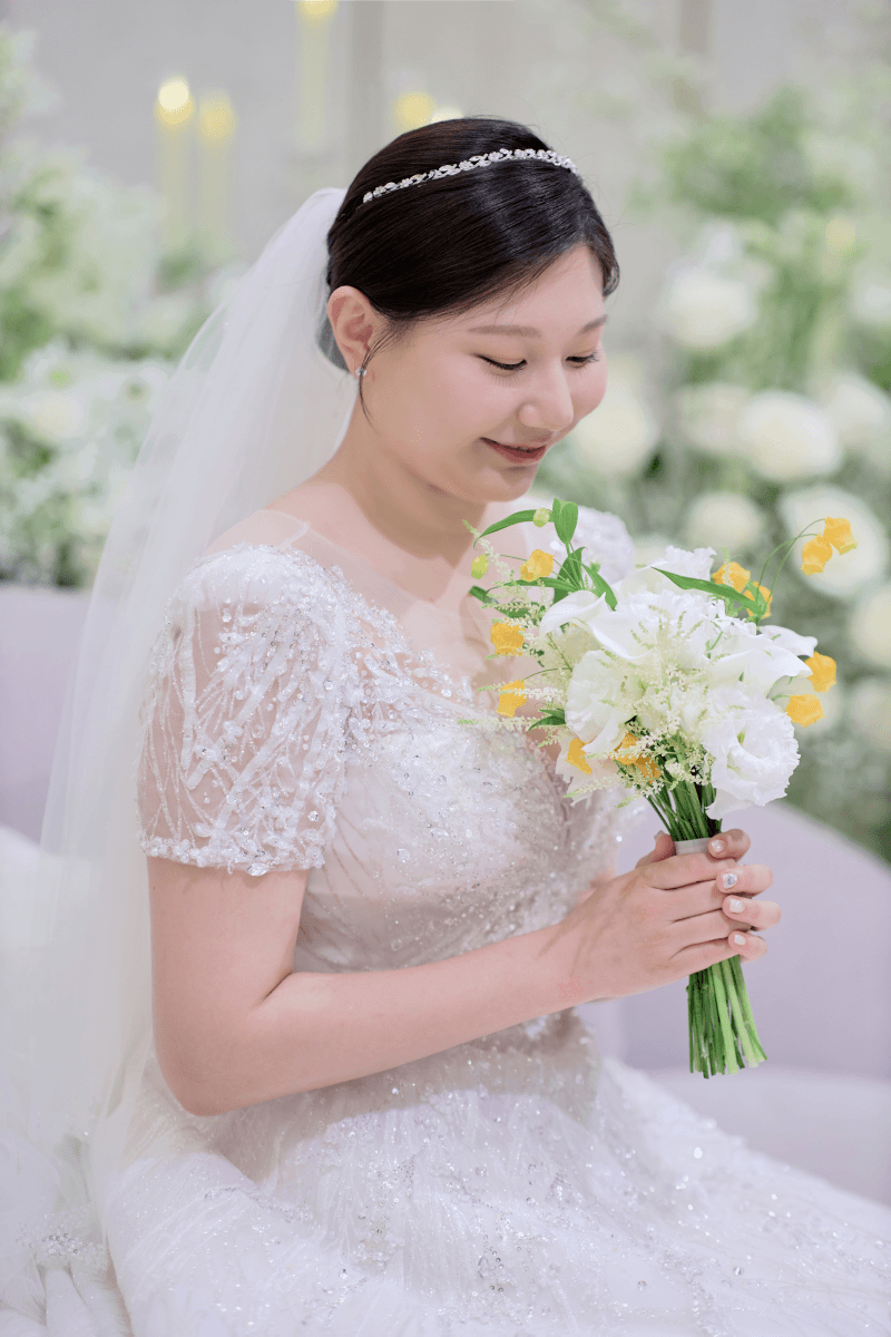 화이트 플라워 앞에서 부케를 든 신랑신부와 신부 클로즈업 2
